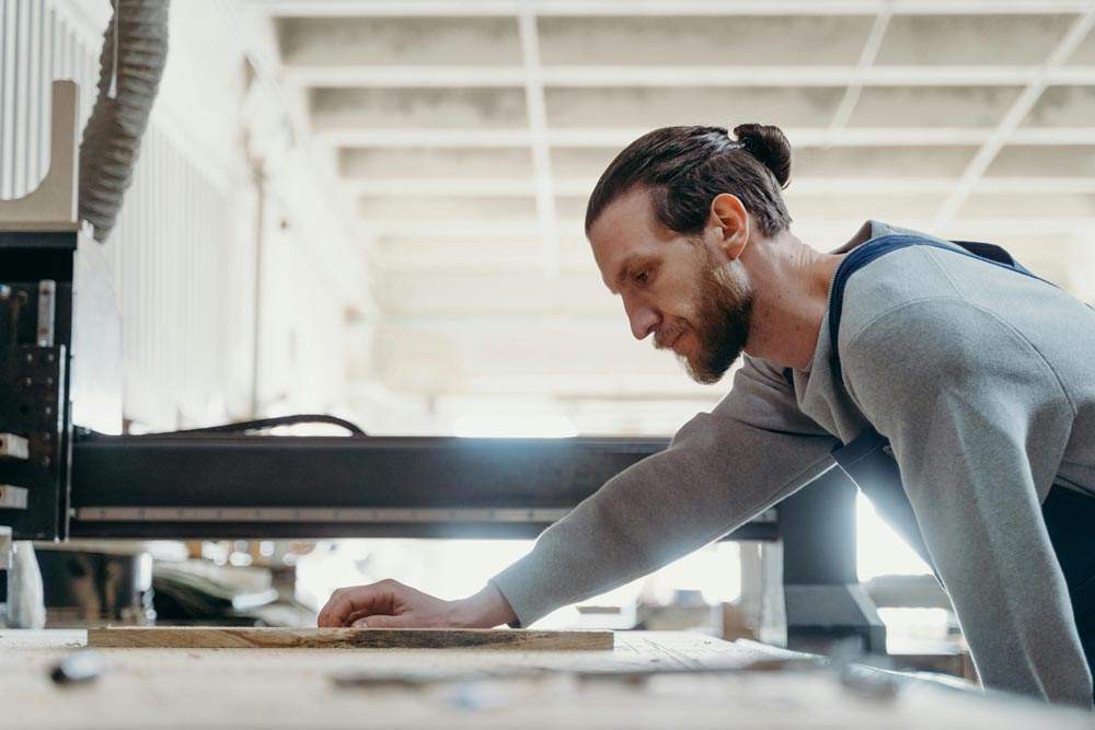 Bearded man using a cnc machine to chop wood